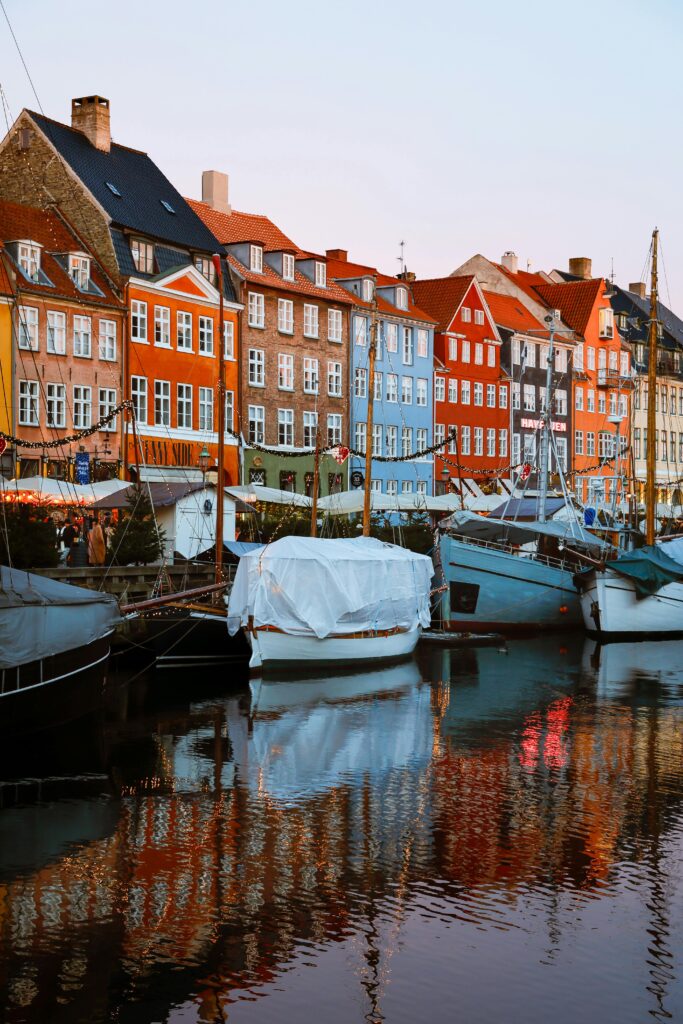 Charming view of colorful historic buildings and boats in Nyhavn, Copenhagen at sunset.